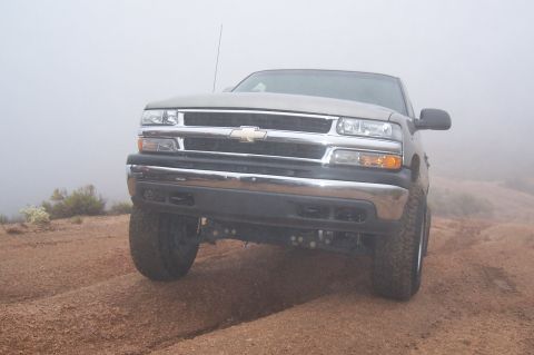 1992 Ford Bronco - Silver Chevrolet pickup truck navigates a foggy dirt road.