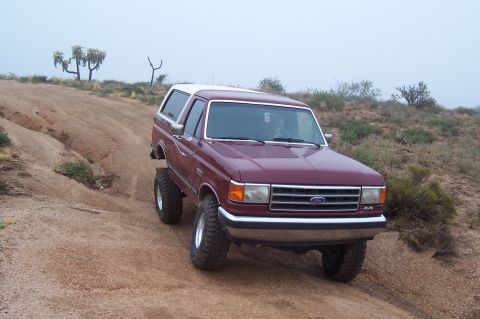 1992 Ford Bronco - This 1992 Ford Bronco, with its distinctive white top, navigates a dusty, off-road trail.