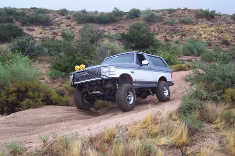 1992 Ford Bronco - This modified Ford Bronco navigates a dusty trail in a , arid landscape.