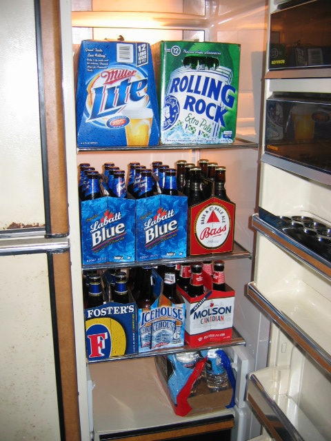 1985 Ford LTD Crown Victoria - A refrigerator is filled with a variety of beer cases and bottles, ready for consumption.