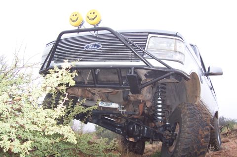 1992 Ford Bronco - A modified Ford truck is shown from a low angle, highlighting its off-road suspension and front grille.