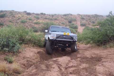 1992 Ford Bronco - This 1992 Ford Bronco navigates a dusty, off-road trail with a custom front bumper and decorative smiley face lights.
