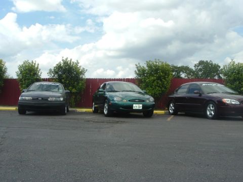 1993 Ford Taurus - Three Ford Taurus sedans are parked in a lot on a cloudy day.