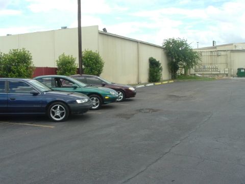 1993 Ford Taurus - Three sedans parked in a lot next to a building.