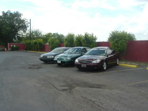 1993 Ford Taurus - Three Ford Taurus sedans are parked in a lot under a cloudy sky.