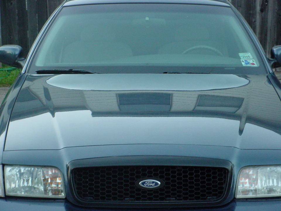 Front view of a blue Ford Crown Victoria with a honeycomb grille and a 2006 inspection sticker on the windshield