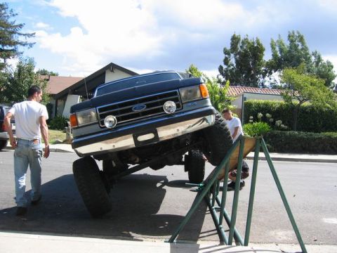 1989 Ford Bronco - A dark blue Ford F-Series truck is positioned on a ramp with its front end elevated.