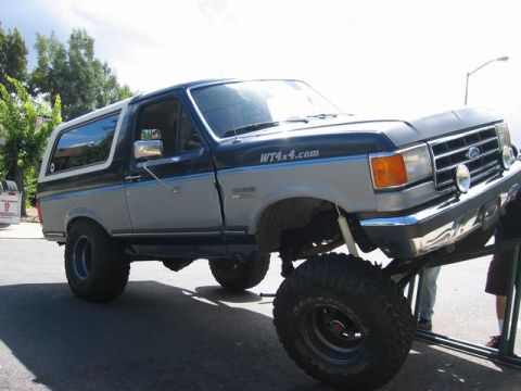 1989 Ford Bronco - This two-tone 1989 Ford Bronco is shown elevated on a ramp, with a WT4x4.com decal visible on its side.