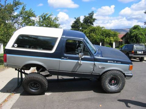 1989 Ford Bronco - A modified Ford Bronco is shown on jack stands with its front end raised.