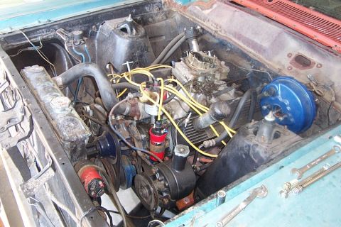 1966 Ford Fairlane - The engine bay of a 1966 Ford Fairlane shows its V8 engine, carburetor, and yellow spark plug wires, indicating it is ready for maintenance.
