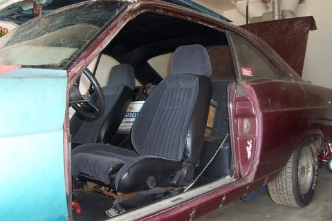 1966 Ford Fairlane - The interior of a classic car shows dark seats and a partially painted door, with a bucket inside.