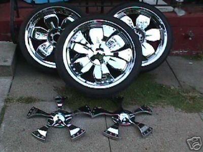 1995 Ford Bronco - A set of four chrome wheels and two hubcaps are displayed on a concrete patio.