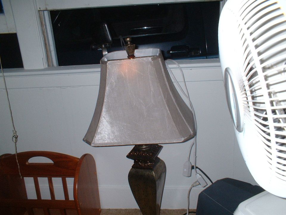 Interior room scene with a table lamp, a white fan, and a wooden crib