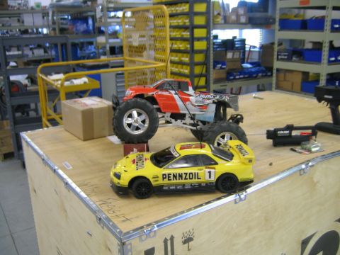 1994 Ford Bronco - RC cars on display in a warehouse setting, with shelving and equipment in the background.