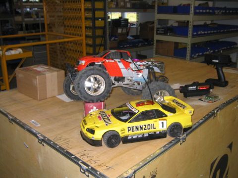 1994 Ford Bronco - RC cars, a monster truck and a sports car, are displayed on a wooden surface with a remote control and accessories nearby.