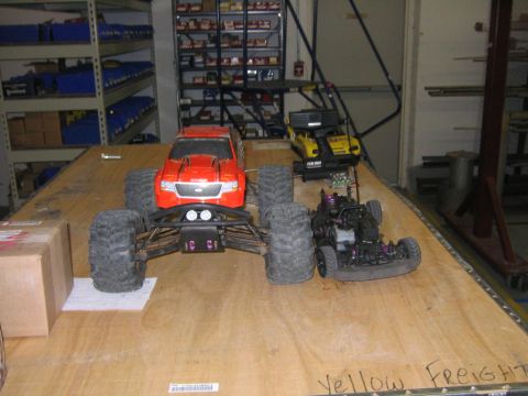 1994 Ford Bronco - Three remote-controlled vehicles are displayed on a wooden surface in what appears to be a workshop or storage area.