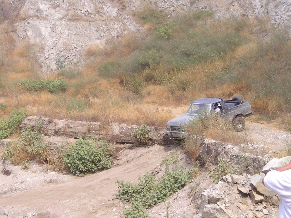 Gray Ford Bronco driving on a dirt path with rocky terrain