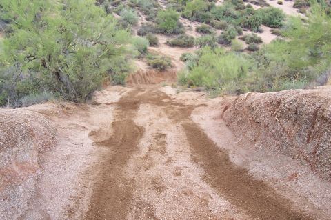 1992 Ford Bronco - A rough dirt path winds through arid terrain, marked by tire tracks from previous travel.