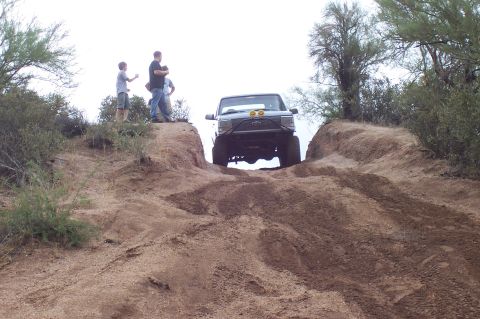 1992 Ford Bronco - A 1992 Ford Bronco navigates a steep dirt incline in a dry, outdoor environment.