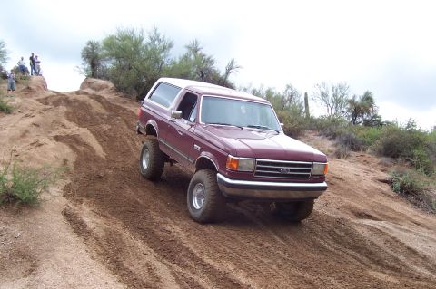 1992 Ford Bronco - Maroon 1992 Ford Bronco tackles a challenging dirt incline off-road.