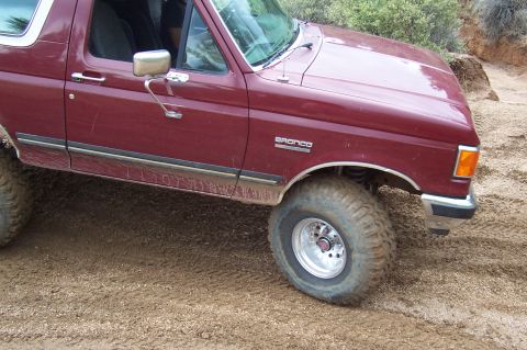 1992 Ford Bronco - This maroon Ford Bronco is shown on a dirt trail with large off-road tires.