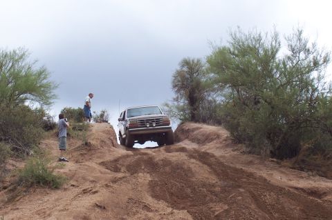 1992 Ford Bronco - A 1992 Ford Bronco navigates a steep dirt incline in a desert landscape.