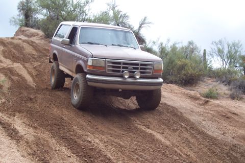 1992 Ford Bronco - This 1992 Ford Bronco is shown off-roading on a steep dirt hill in a desert environment.