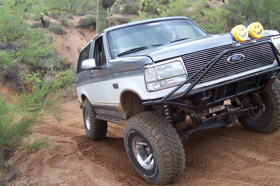 1992 Ford Bronco, two-tone, custom bumper, off-road tires, driving on dirt