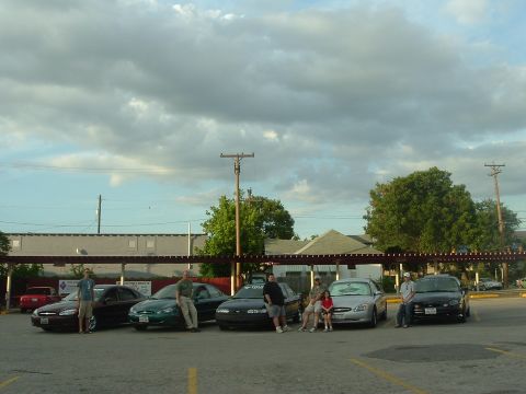1993 Ford Taurus - Several Ford Taurus sedans are parked in a lot, with people standing and sitting around them.