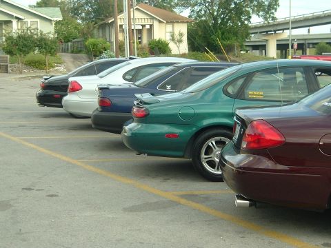 1993 Ford Taurus - Several cars are parked in a lot, showing their rear ends and taillights.