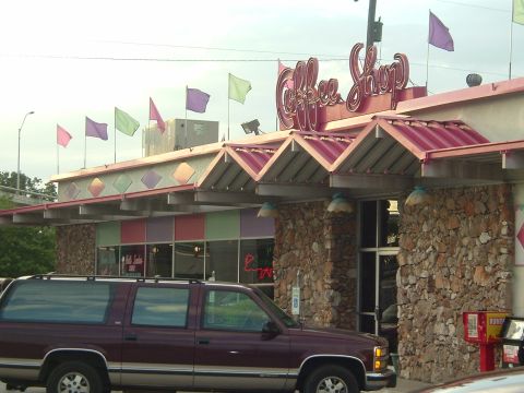 1993 Ford Taurus - A maroon SUV is parked outside a coffee shop with a distinctive roofline and signage.