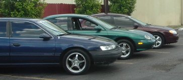 1993 Ford Taurus - Three sedans, including a 1993 Ford Taurus, are parked in a lot.