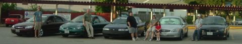 1993 Ford Taurus - Multiple Ford Taurus sedans are lined up, with several people posing next to them.