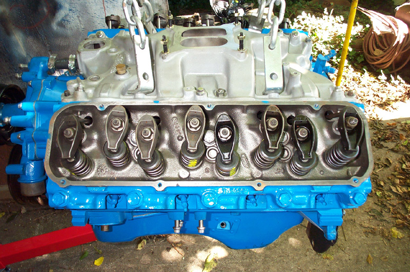 Rebuilt blue V8 short-block on a stand outdoors with heads and intake installed