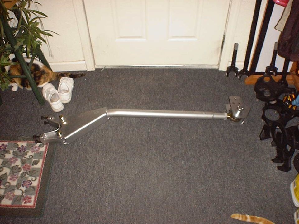 Custom silver radius arm with boxed plate end and tube shaft laid on carpet