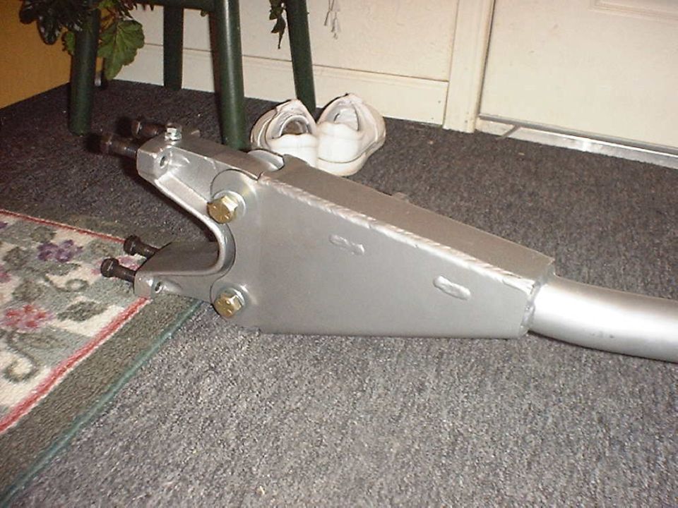 Silver fabricated radius arm suspension link with welded plate boxing lying on carpet