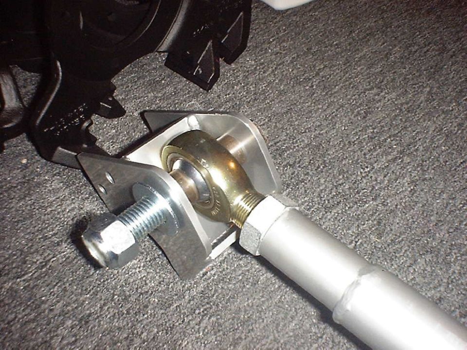Gold heim joint in silver tube link bolted into a steel weld-on bracket