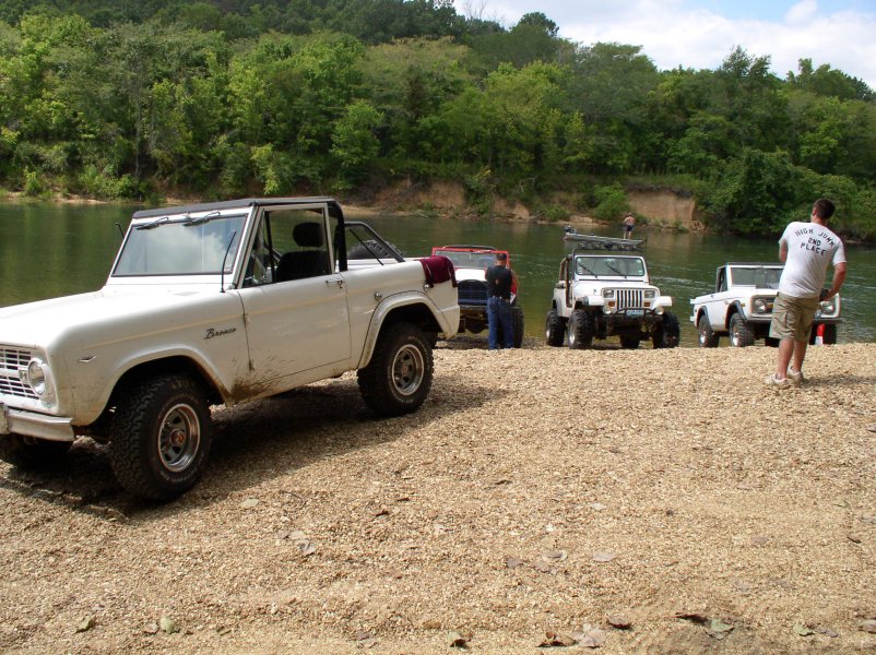 White 1966 Ford Bronco parked on a gravel shore, side view