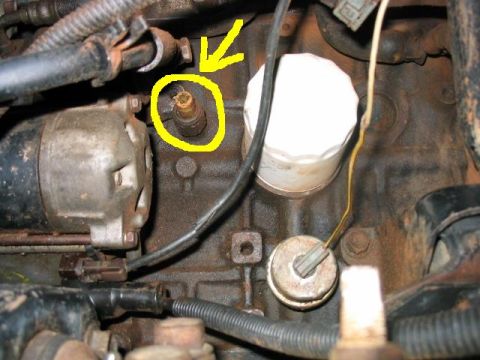 1986 Ford F-150 - Engine block detail showing starter, oil filter, and a sensor highlighted with a yellow circle and arrow.