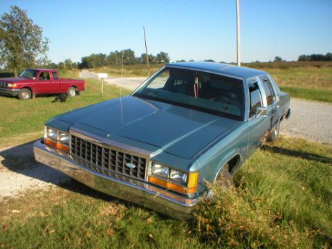 1987 Ford Crown Victoria LTD - Blue 1987 Ford Crown Victoria LTD sits on a grassy shoulder next to a gravel road.