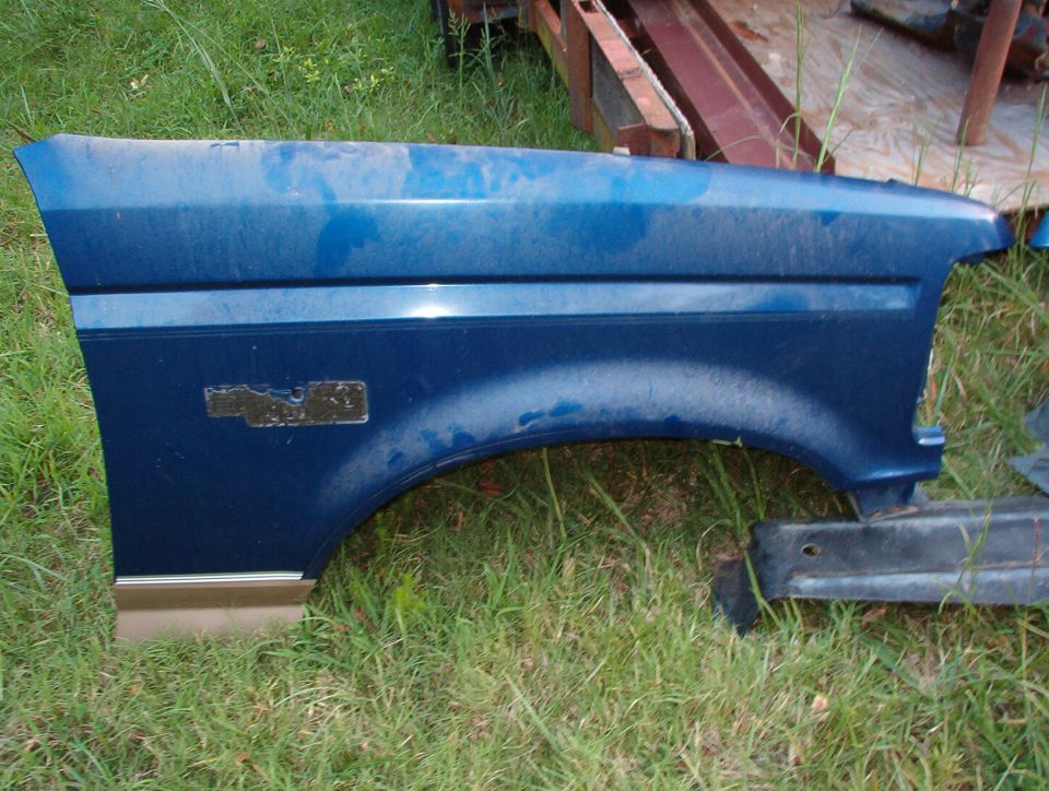 Blue automotive front fender panel resting on grass