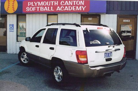 1999 Jeep Grand Cherokee - A white 1999 Jeep Grand Cherokee is parked outside the Plymouth Canton Softball Academy.