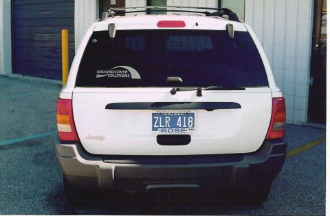 1999 Jeep Grand Cherokee - Rear view of a 1999 Jeep Grand Cherokee showing its license plate and a 'Groundcover Solutions' sticker.