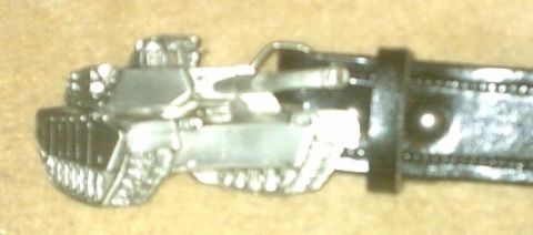 1992 Ford Bronco - A metal belt buckle shaped like a tank is attached to a black leather belt.