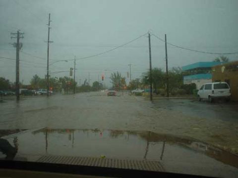 1989 Ford Bronco - Vehicles navigate a flooded street under an overcast sky, with a white van parked on the right.