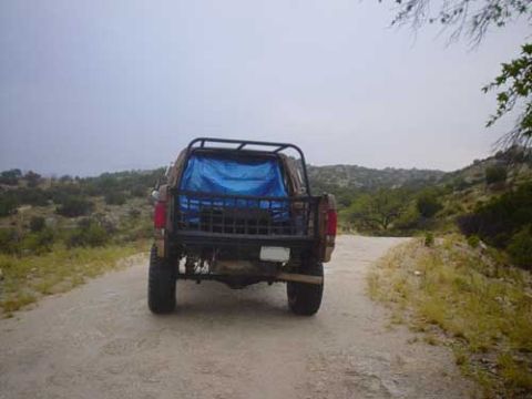 1989 Ford Bronco - This 1989 Ford Bronco is parked on a dirt road with hills and trees in the background.