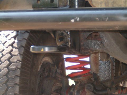 1979 Ford Bronco - Close-up view of a vehicle's suspension system, including a red coil spring and tire.