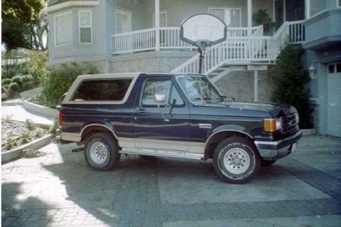 1991 Ford Bronco - Dark blue 1991 Ford Bronco with tan trim parked in front of a house.