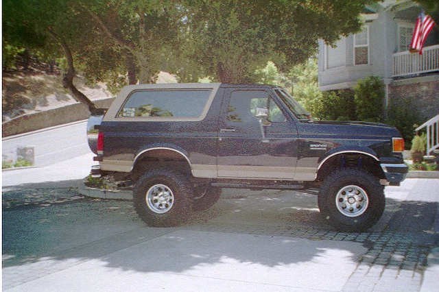 Side view of a dark blue and tan 1991 Ford Bronco with lifted suspension