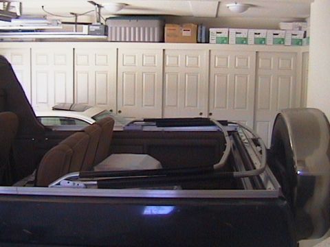 1991 Ford Bronco - The interior of a dark SUV is visible, with brown seats and a white car in the background.